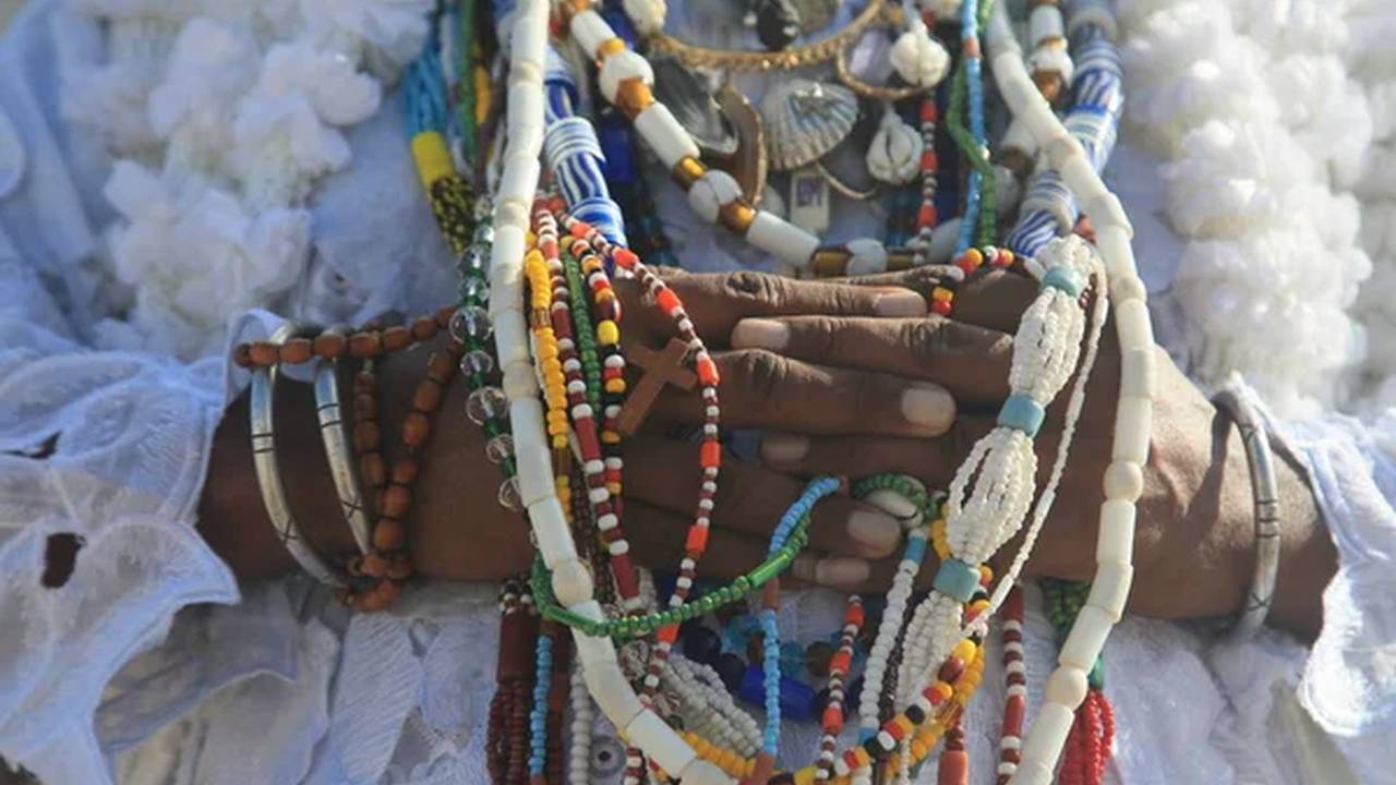 Mãos com contas e colares coloridos, em cerimônia religiosa de Umbanda.