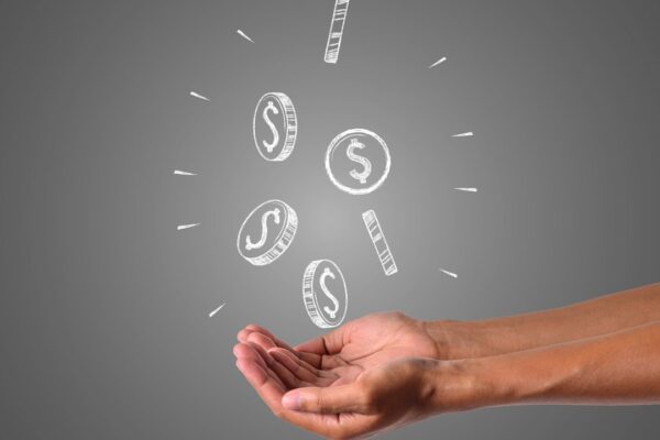 Mãos segurando moedas de dólar caindo, simbolizando dinheiro e finanças.