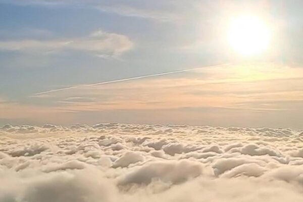 Mar de nuvens sobre a cidade de Nova Friburgo com o sol brilhando no céu azul.