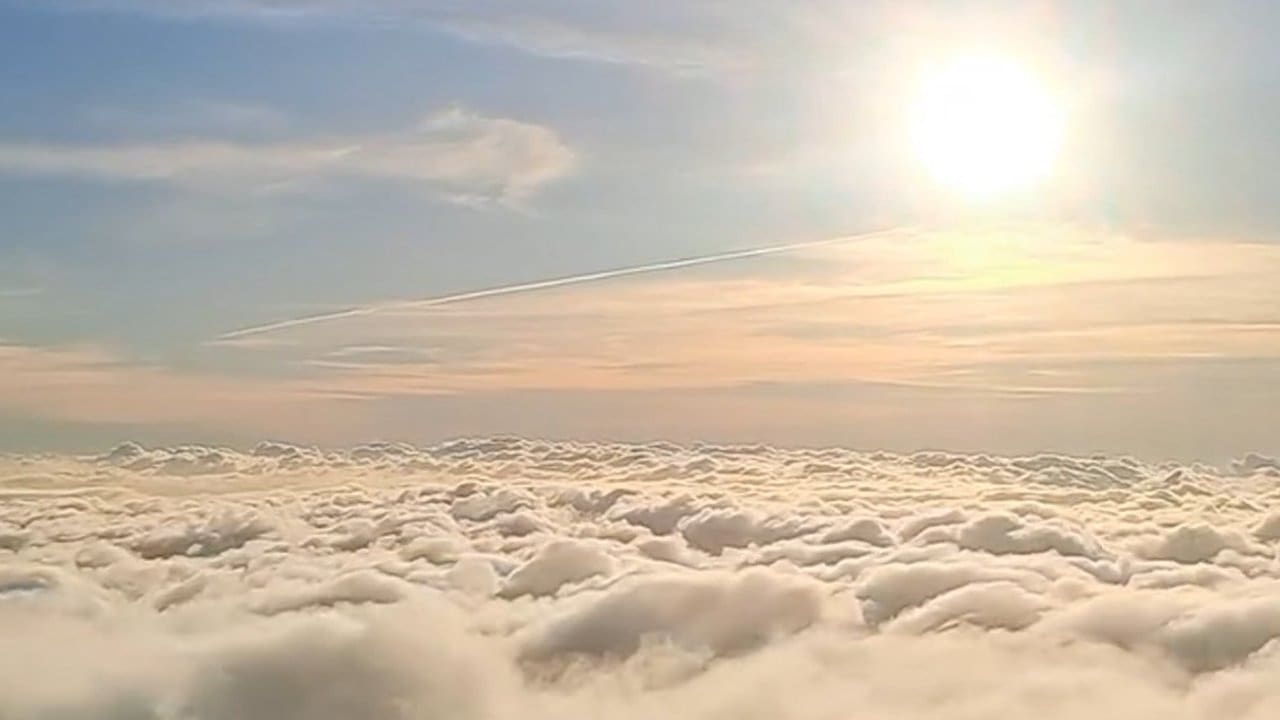 Mar de nuvens sobre a cidade de Nova Friburgo com o sol brilhando no céu azul.