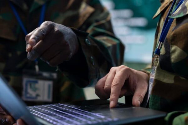 Militares usando laptop em ambiente de trabalho.
