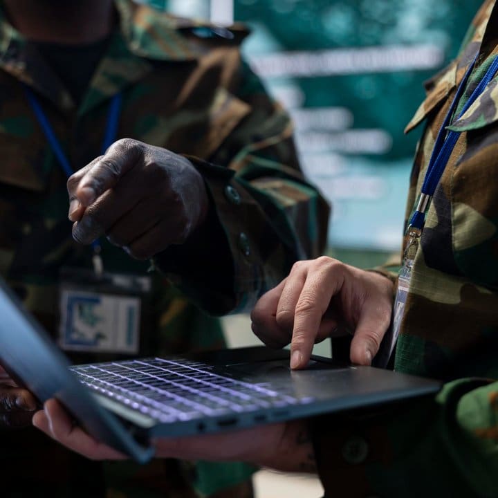 Militares usando laptop em ambiente de trabalho.