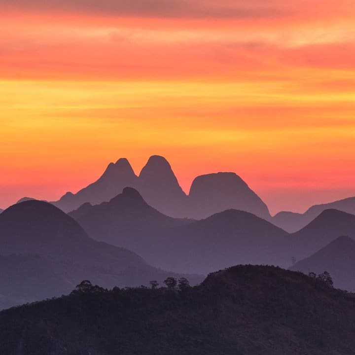Montanhas em silhueta sob um céu vibrante no pôr do sol, vista Três Picos.