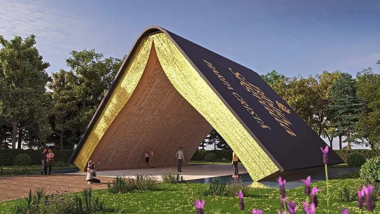 Monumento gigante em forma de livro aberto no centro de um jardim, com pessoas em volta