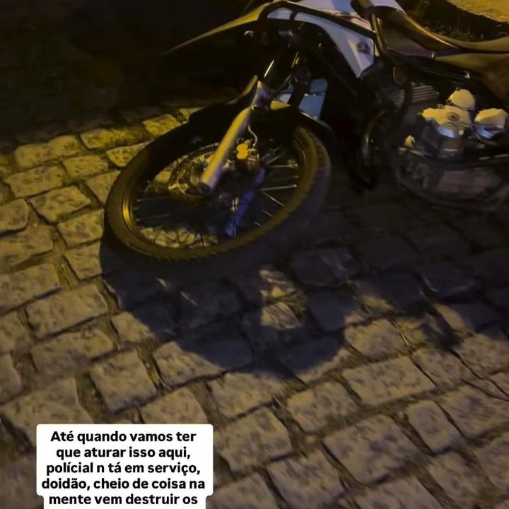 Motocicleta em calçada de paralelepípedos, com texto sobre violência policial.