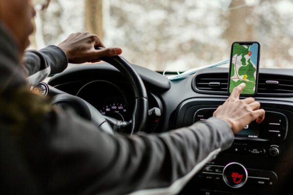 Motorista usando aplicativo de GPS em um carro, com mapa aberto no celular.