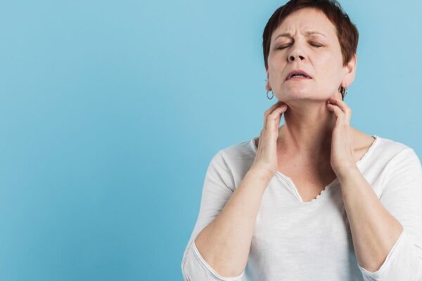 Mulher com sintomas de gripe tocando o pescoço
