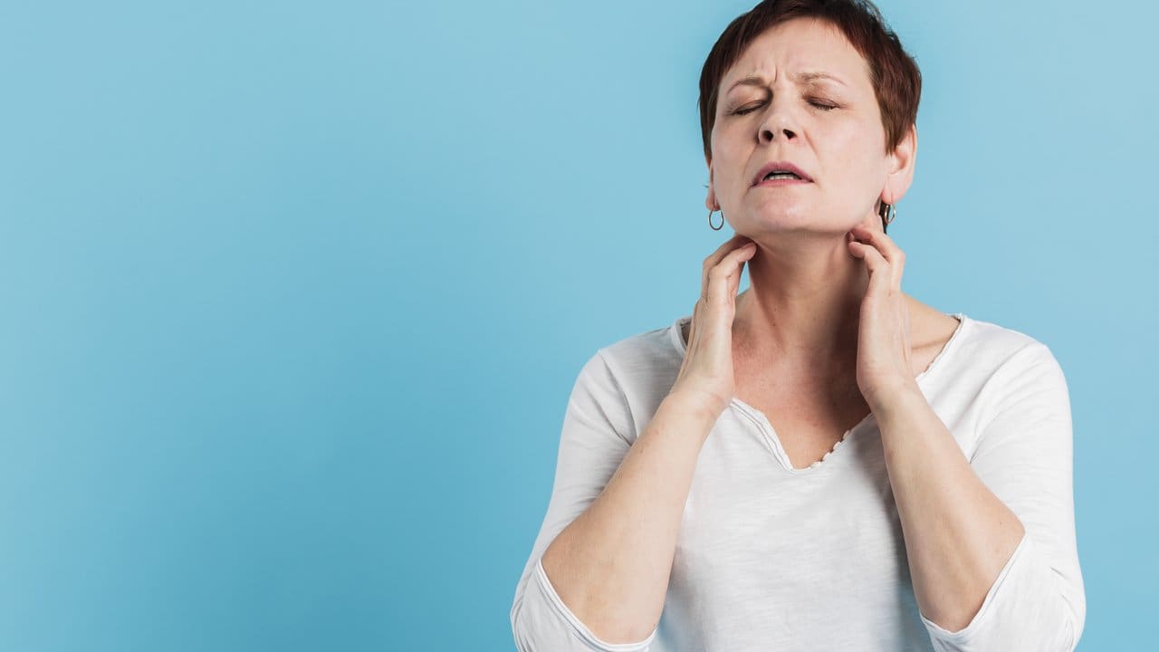 Mulher com sintomas de gripe tocando o pescoço