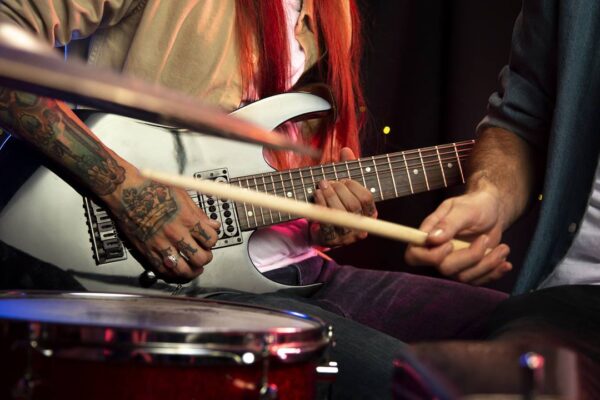 Músicos tocando guitarra e bateria em um evento ou show.