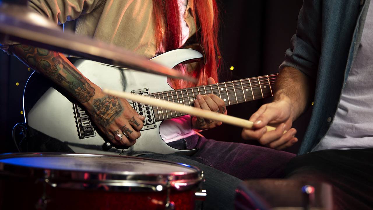 Músicos tocando guitarra e bateria em um evento ou show.