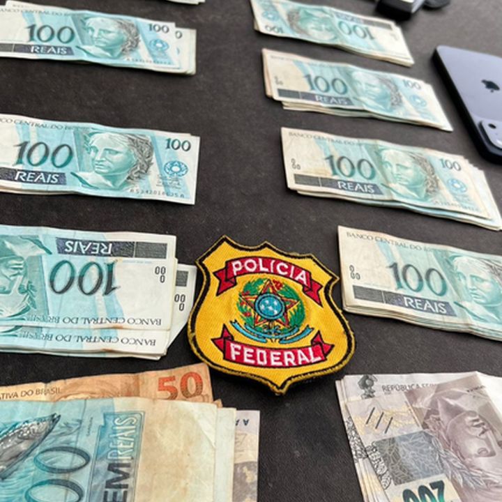 Notas de dinheiro e distintivo da Polícia Federal em apreensão.