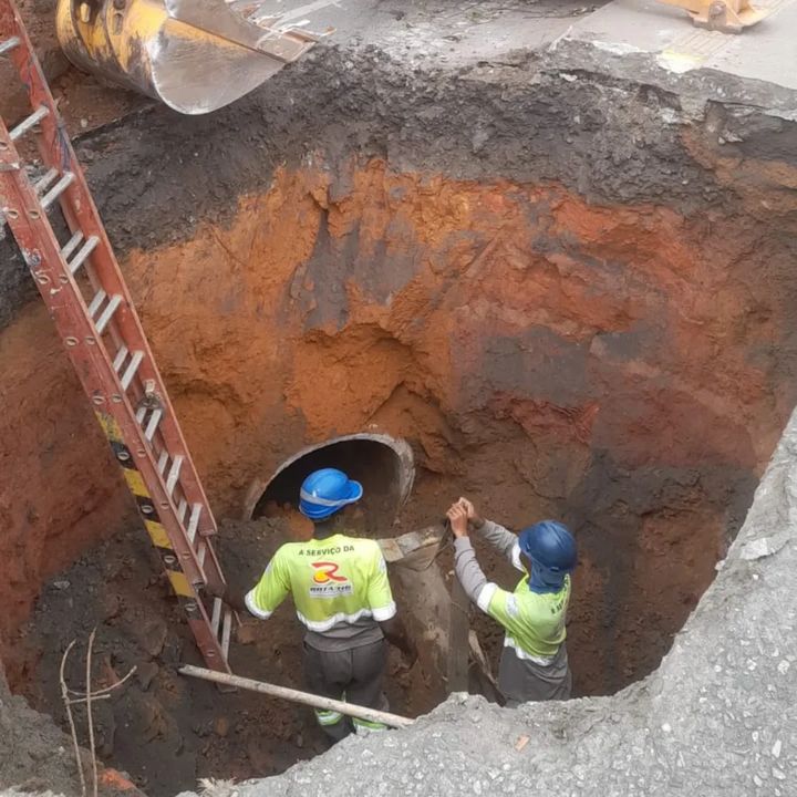 Obras de emergência em rodovia no Rio de Janeiro, com trabalhadores e escavação.