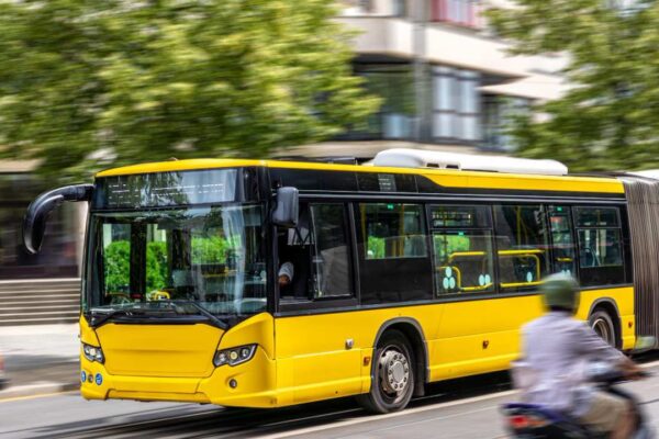 Ônibus amarelo em movimento em cidade.