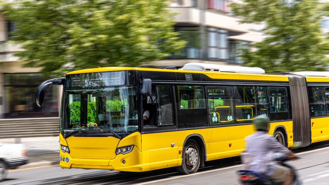 Ônibus amarelo em movimento em cidade.