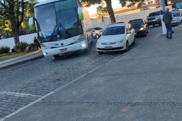 Ônibus de turismo parado em rua, causando congestionamento em Nova Friburgo.