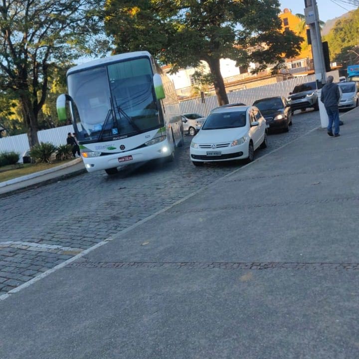 Ônibus de turismo parado em rua, causando congestionamento em Nova Friburgo.