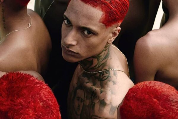 Oruam com cabelo vermelho e tatuagens no pescoço e peito, em meio a outros com cabelos vermelhos.