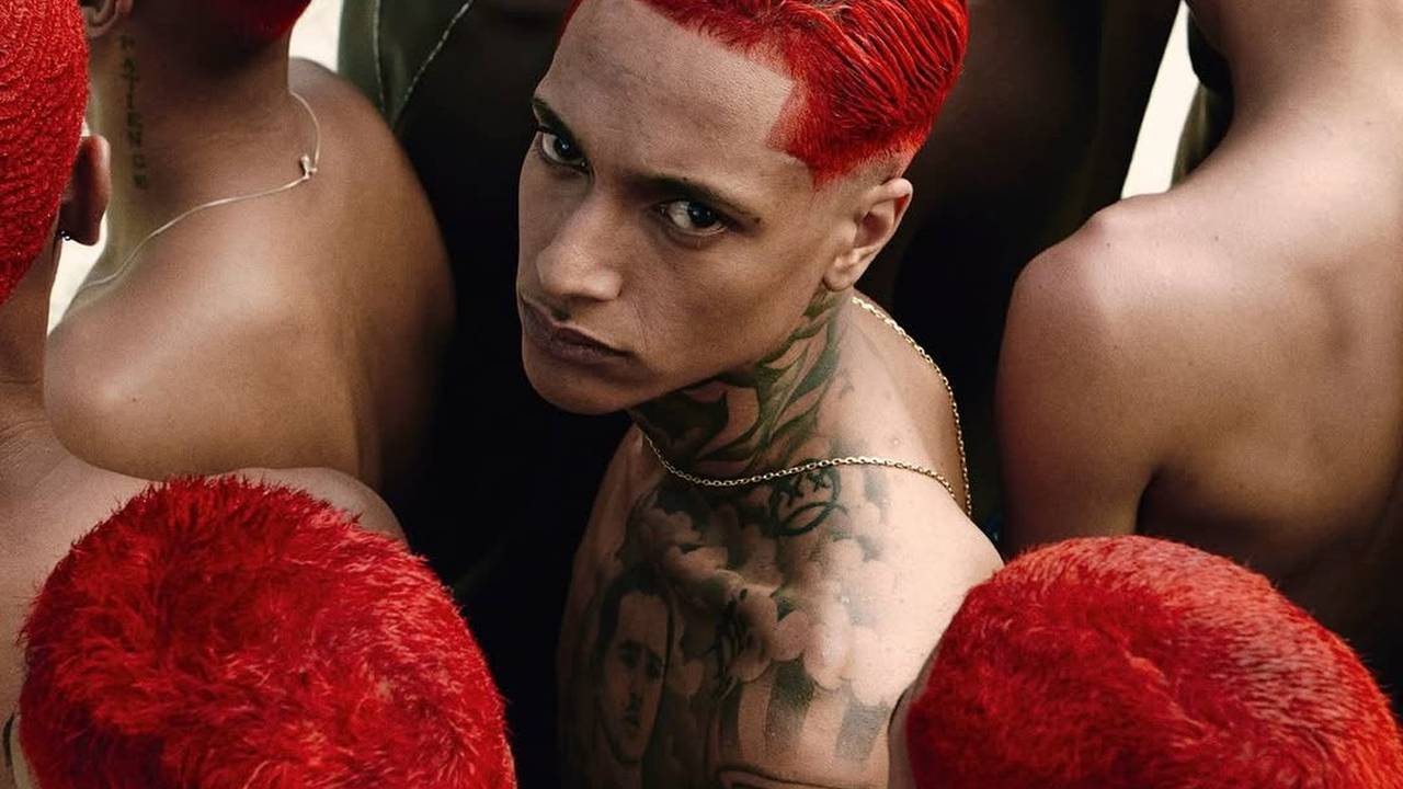 Oruam com cabelo vermelho e tatuagens no pescoço e peito, em meio a outros com cabelos vermelhos.