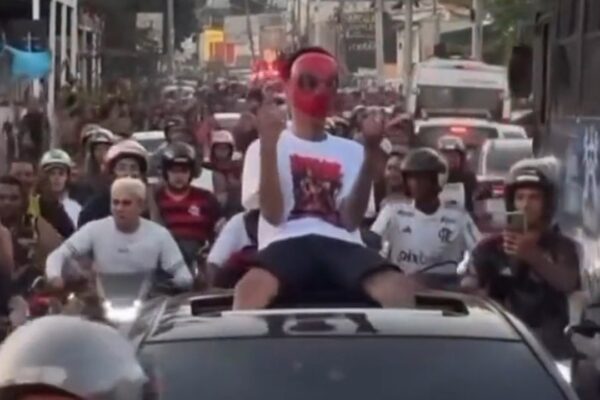 Oruam com máscara vermelha em carro aberto cercado por multidão em Bangu