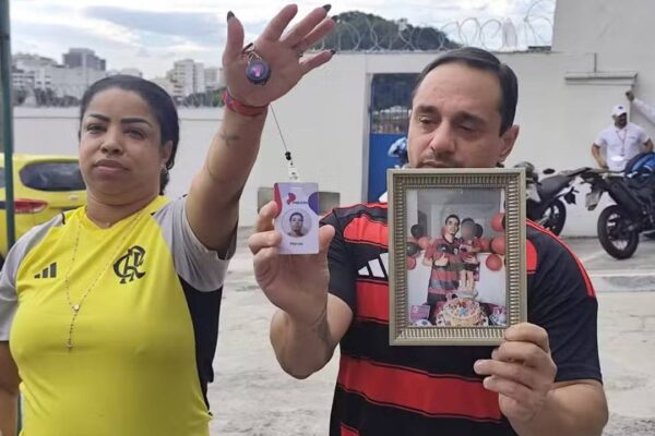 Pais de Herus em velório de vítima do BOPE seguram fotos e identificação.