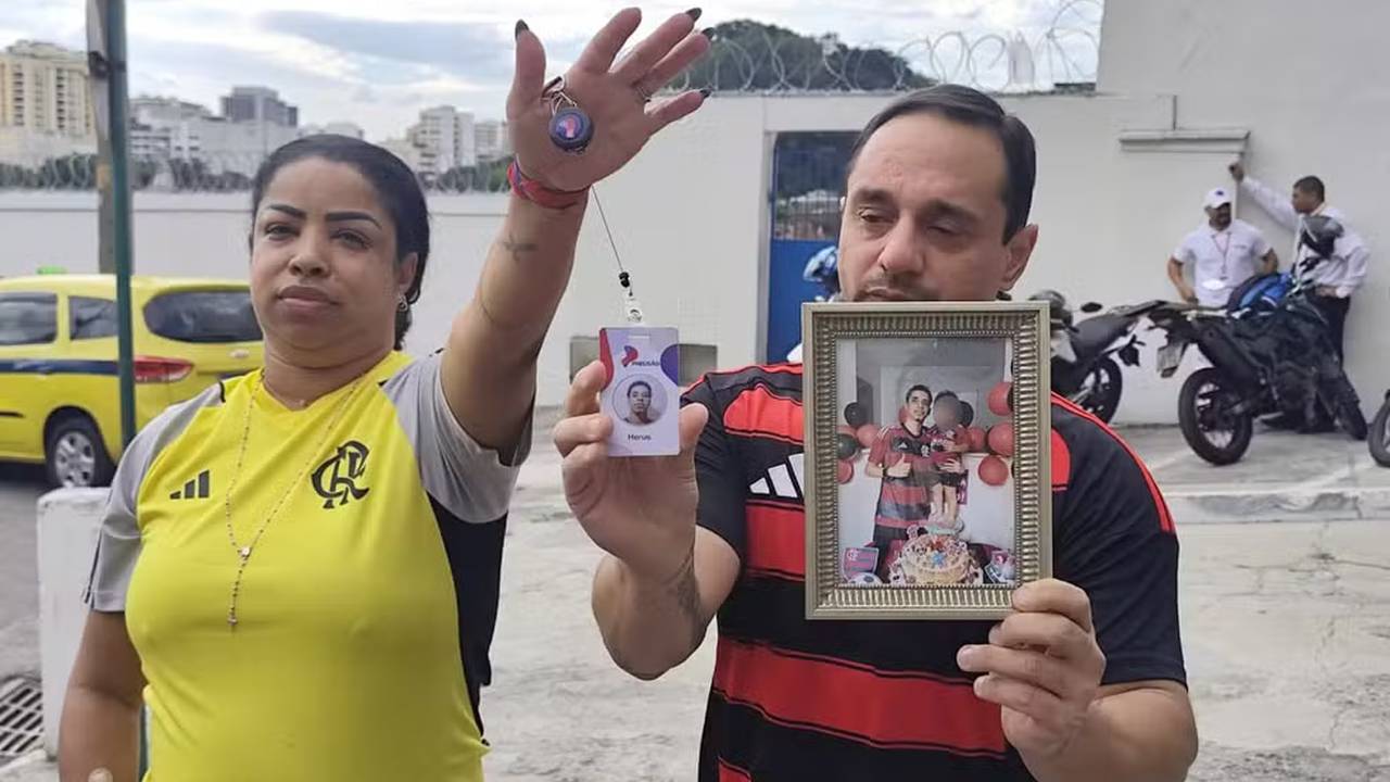 Pais de Herus em velório de vítima do BOPE seguram fotos e identificação.