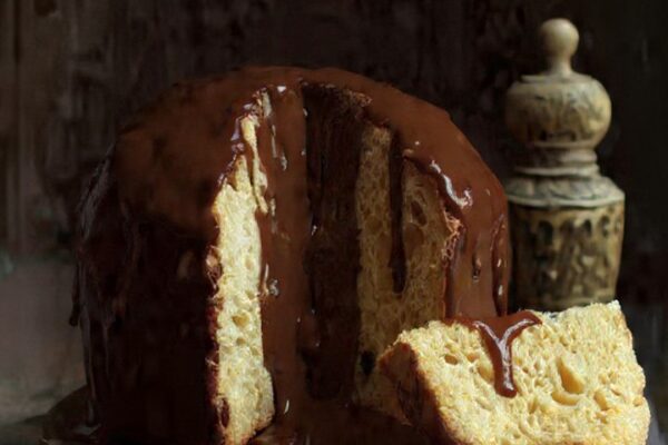 Panetone com cobertura de chocolate e fatia cortada.