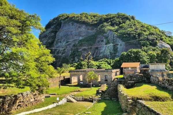 Parque Histórico Monte Bastione em Niterói com ruínas, vegetação exuberante e vista da montanha.