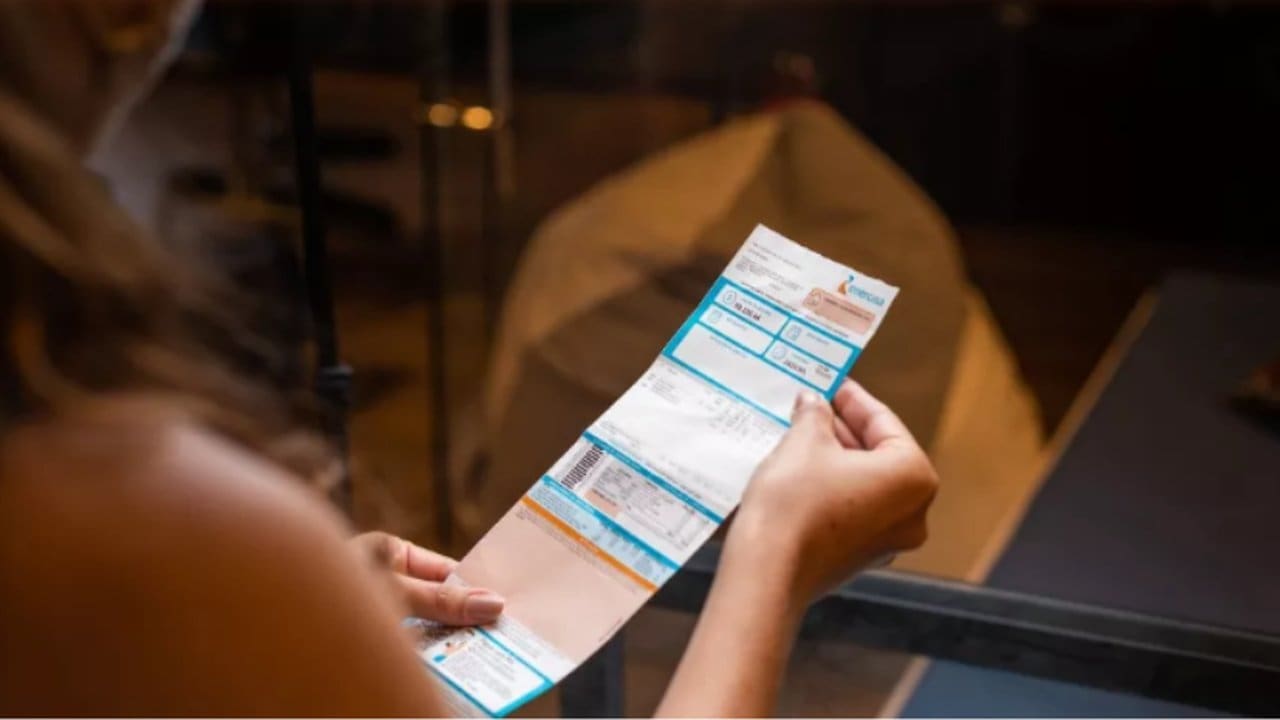 Pessoa segurando conta da Energisa, que oferece negociação digital de débitos.