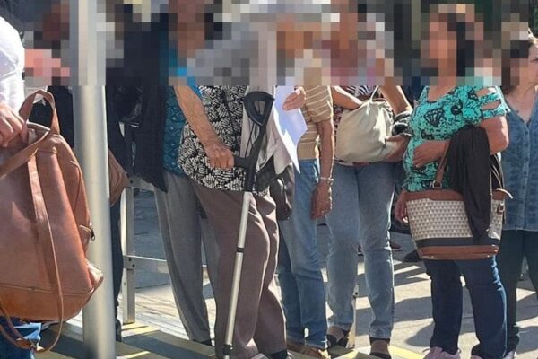 Pessoas em fila para atendimento médico, com foco em idosos e pessoas com bengala.