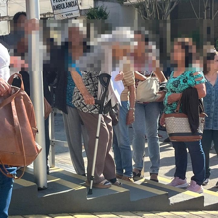 Pessoas em fila para atendimento médico, com foco em idosos e pessoas com bengala.