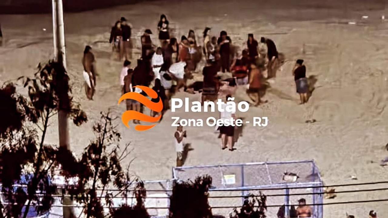 Pessoas em uma praia à noite, com um logotipo 'Plantão Zona Oeste - RJ' sobreposto.