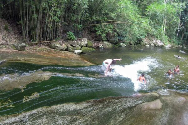 Pessoas se divertindo na Cachoeira do Escorrega, um tobogã natural em meio à natureza exuberante.
