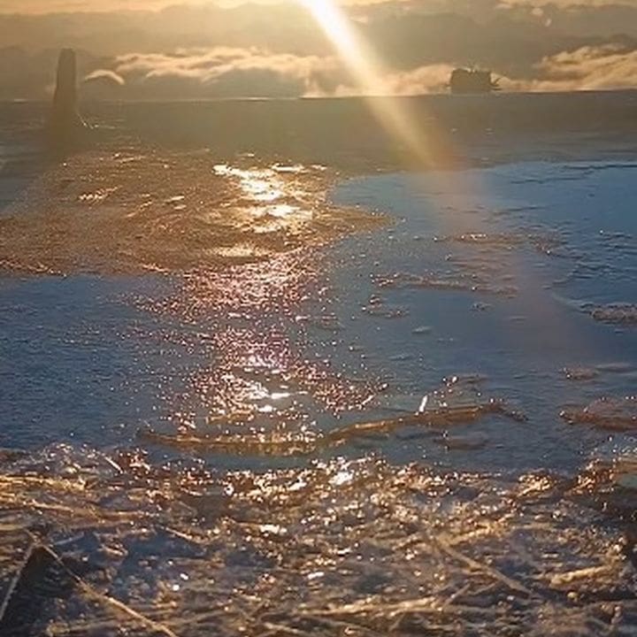 Pico do Caledônia congelado em Nova Friburgo, com sol nascendo e reflexos na água congelada.