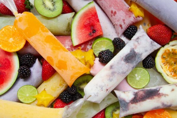 Picolés de frutas coloridos: morango, kiwi, laranja, limão e amora.