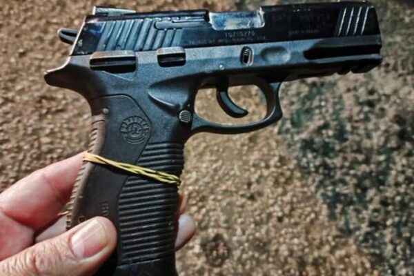 Pistola preta, usada em crime, vista de cima, foco na arma e não na pessoa.