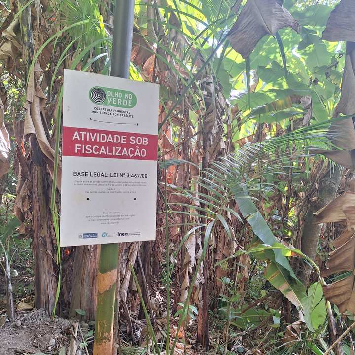 Placa de fiscalização 'Olho no Verde' em área florestal.