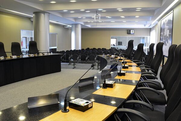 Plenário da Câmara Municipal de Nova Friburgo com cadeiras e mesa.