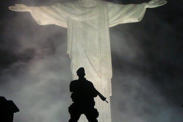 Policial em frente ao Cristo Redentor, simbolizando a segurança no Rio de Janeiro.