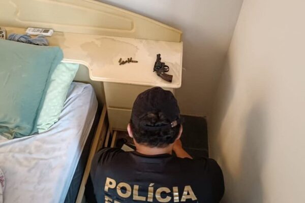 Policial federal investiga local com arma e munições durante operação.