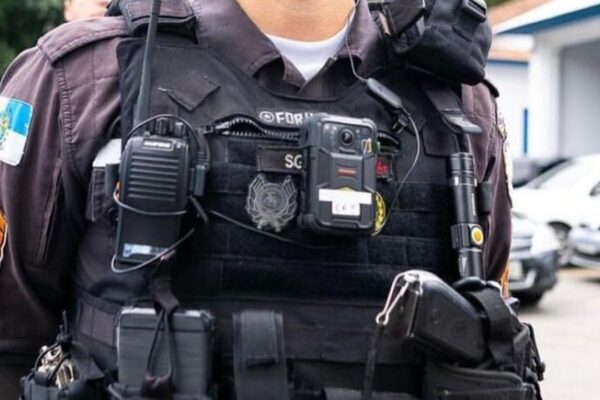 Policial militar com colete à prova de balas e equipamentos, possivelmente em operação.