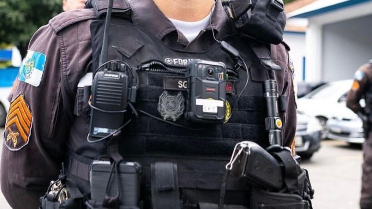 Policial militar com colete à prova de balas e equipamentos, possivelmente em operação.
