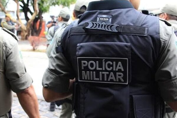 Policial militar com colete tático e a inscrição 'Polícia Militar'.