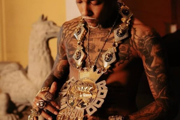 Poze do Rodo com colar de ouro e tatuagens.