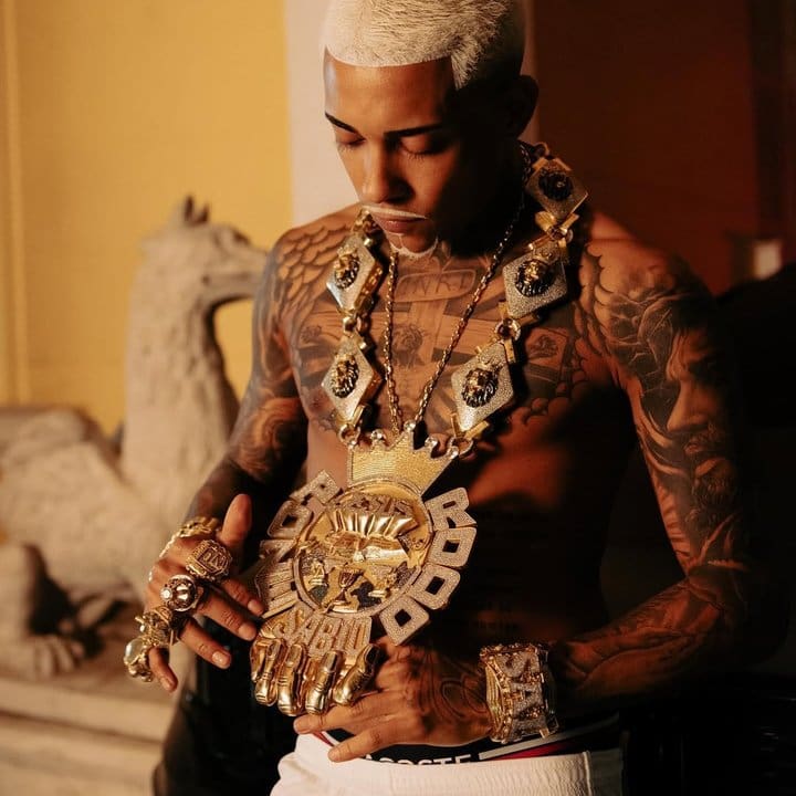 Poze do Rodo com colar de ouro e tatuagens.