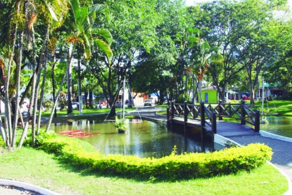 Praça Doutor José Bonifácio com lago e vegetação exuberante, em clima bucólico.