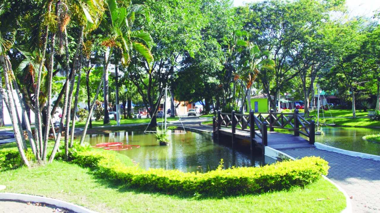 Praça Doutor José Bonifácio com lago e vegetação exuberante, em clima bucólico.