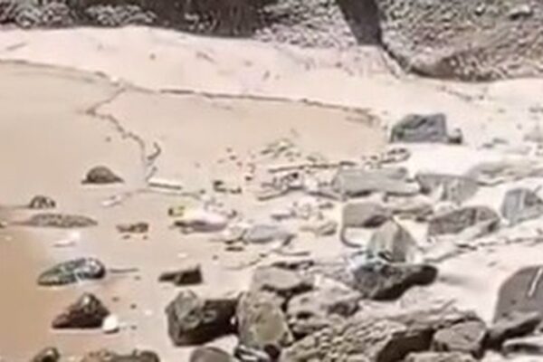 Praia com pedras e areia, possivelmente local de encontro de corpo esquartejado.