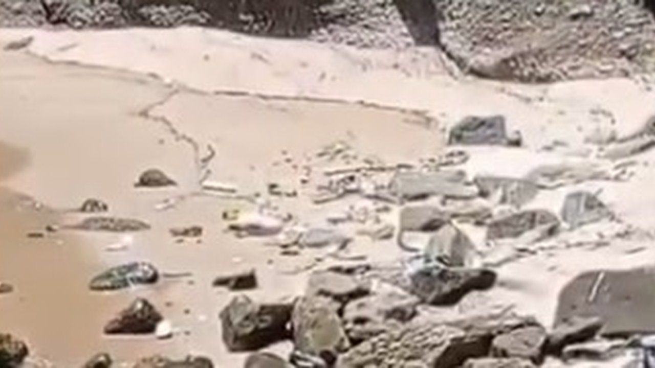 Praia com pedras e areia, possivelmente local de encontro de corpo esquartejado.