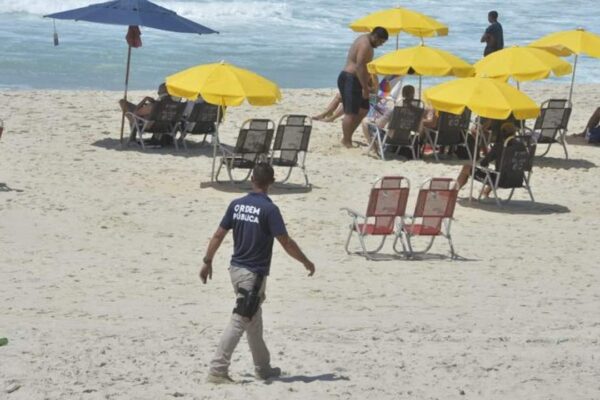 Praia de Copacabana com guarda municipal, guarda-sóis e pessoas