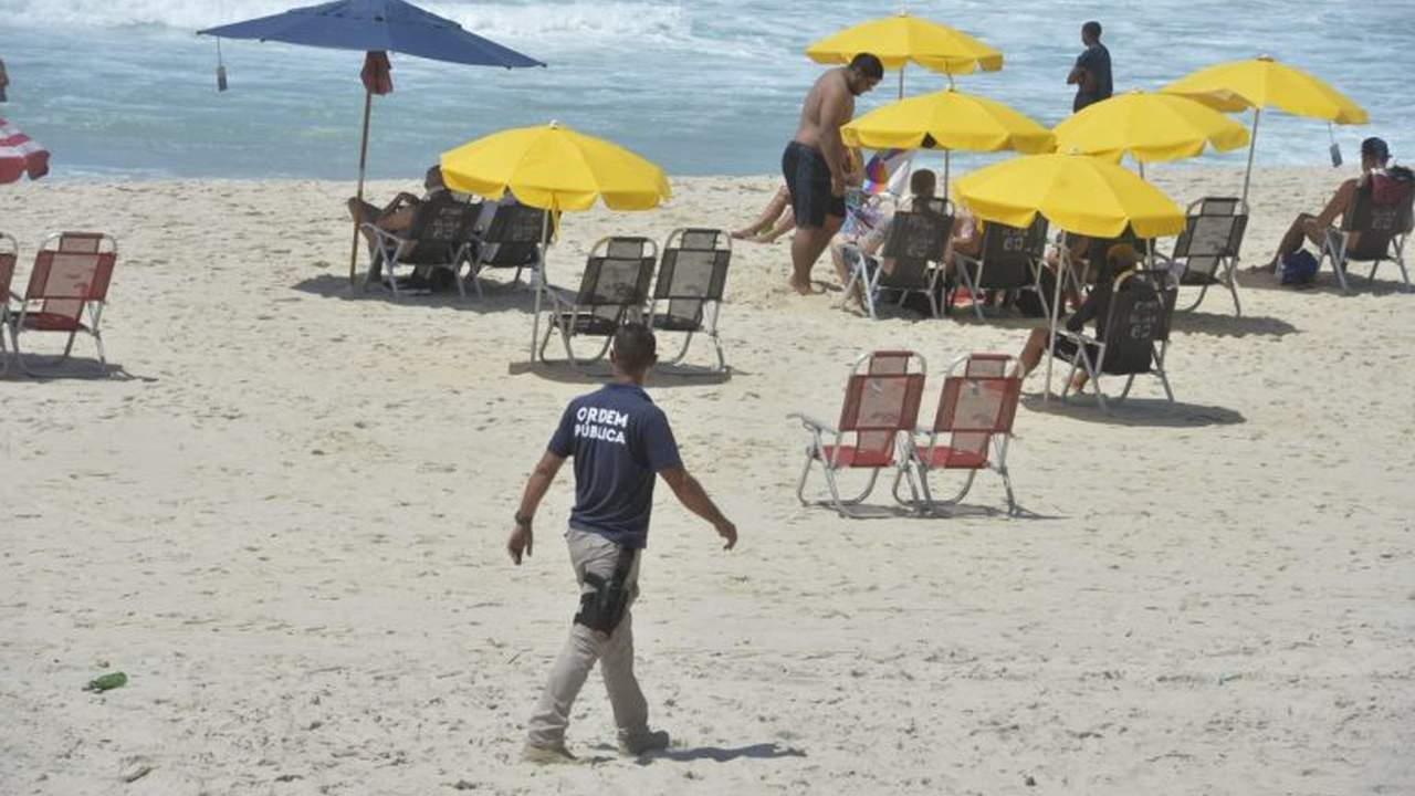 Praia de Copacabana com guarda municipal, guarda-sóis e pessoas